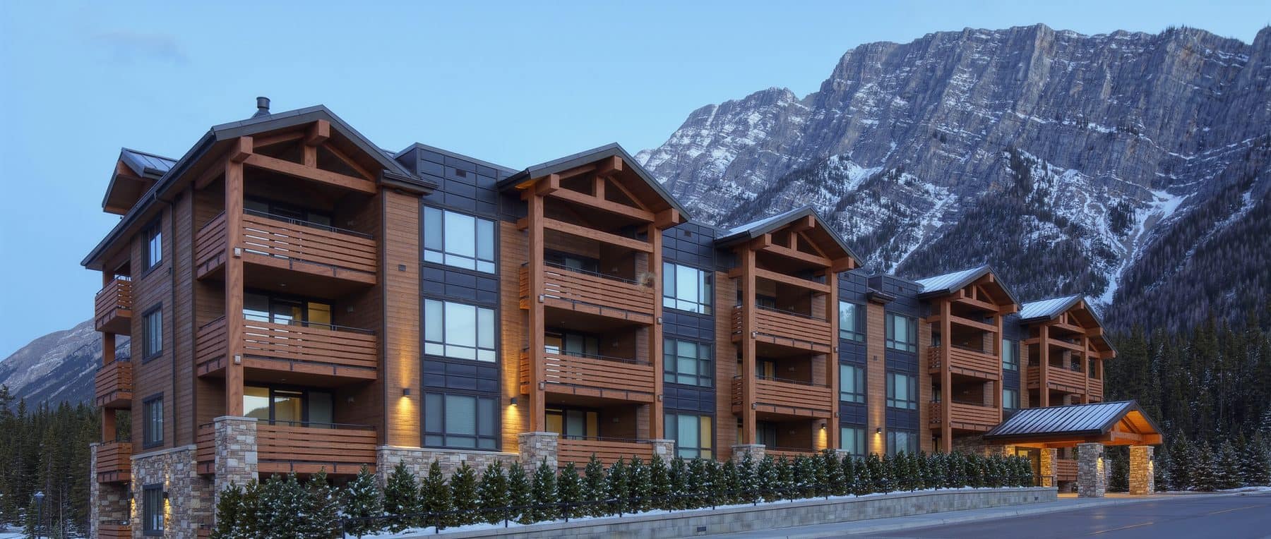 Alberta condo law in practice: a modern Canmore apartment condominium building below snow-dusted Rocky Mountain ridges