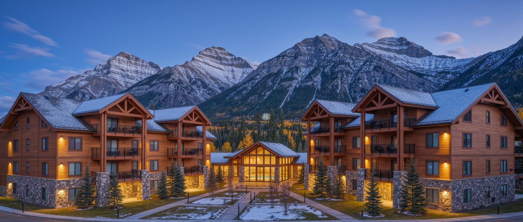 Crossbow Place Canmore: four low-rise condominium buildings around a courtyard below the Three Sisters peaks
